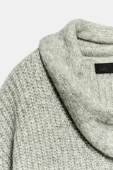 Jersey de punto de corte holgado en color gris jaspeado, con escote en pico y bufanda integrada del mismo tejido. Presenta mangas largas con puños ajustados.