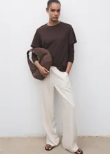 Pantalón largo color blanco crudo, de corte recto y tiro medio, con cintura elástica y cordón ajustable. Cuenta con dos bolsillos laterales.