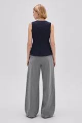 Chaleco negro sin mangas, con cuello redondo y cierre frontal de botones. Presenta un diseño entallado con bolsillos laterales simulados.