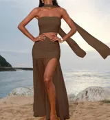 Vestido largo color marrón, de dos piezas. Incluye un top strapless fruncido y una falda larga fruncida con abertura lateral y una capa de tela transparente. También incluye una bufanda a juego.