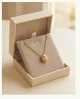 Collar de acero con baño de oro, compuesto por una cadena fina y un dije circular de diseño orgánico y superficie lisa.