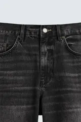 Bermuda de denim de algodón, color azul medio lavado, de corte ancho (baggy fit) y largo hasta la rodilla. Presenta cinco bolsillos y cierre frontal con cremallera y botón.