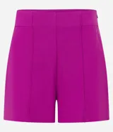 Short corto femenino de cintura alta, color fucsia, confeccionado en bengalina con cierre lateral por cremallera y detalle de pliegues (frisos) en la parte delantera.