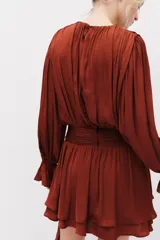 Vestido corto marrón de tejido drapeado con cuello redondo, manga larga abullonada y detalle de nudo en la cintura con tiras colgantes.