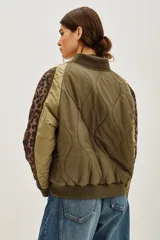 Campera tipo bomber acolchada en color verde militar, con mangas largas que presentan paneles laterales con estampado animal print. Cuenta con cierre frontal, cuello, puños y ruedo en tejido rib elástico.