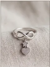 Anillo de plata 925 con diseño del símbolo del infinito y dijes colgantes en forma de estrella y corazón, ambos decorados con circonias.