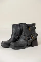 Botas cortas de cuero negro con acabado desgastado, punta cuadrada y taco bloque. Presentan un diseño versátil con estribo desmontable decorado con hebillas metálicas y tachas, permitiendo dos estilos diferentes en un mismo calzado.