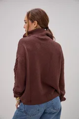 Sweater de punto color marrón chocolate, con cuello alto y cierre frontal parcial. Presenta un diseño con texturas combinadas, incluyendo paneles de punto trenzado en las mangas y el frente, y un tejido de punto texturizado en el centro.