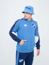 Canguro deportivo Umbro del Club Nacional de Football, modelo Nexo para hombre. Diseño en color azul marino con mangas rojas y detalles en celeste y blanco, capucha con cordón ajustable y bolsillo tipo canguro.