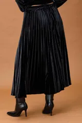 Falda midi plisada de terciopelo negro, con diseño fluido y corte acampanado.