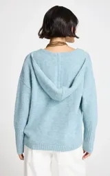 Sweater de punto en color celeste, con diseño de cuello en V y capucha integrada. Presenta mangas largas con puños acanalados y un corte holgado.