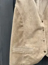 Chaleco sastrero de cuero con efecto desgastado, escote en V, cierre frontal con botones metálicos dorados y bolsillos frontales con solapa.