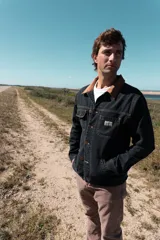 Campera corta de jean negro con cuello de pana marrón, confeccionada en jean grueso 100% algodón de 14 onzas, con costuras marrones en contraste.