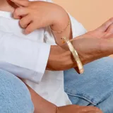 Esclava rígida de oro 18k con acabado satinado y diseño de cinta plana. Presenta una textura fina en su superficie y un diseño minimalista.