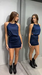 Vestido corto azul marino con cuello halter fruncido, diseño sin mangas, espalda descubierta y falda ajustada con frunces laterales.