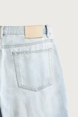 Pantalón jeans de corte recto, color celeste claro con efecto lavado, de cinco bolsillos y tiro medio.