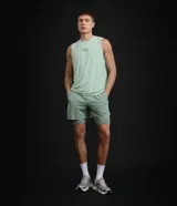 Bermuda deportiva verde militar con short de compresión incorporado, cintura elástica y cordón ajustable, confeccionada en microfibra de poliéster y elastano.