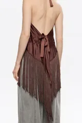 Top de corte fluido color marrón oscuro, con escote halter ajustable mediante cintas anudadas en el cuello. Presenta bordados florales tonales en el frente y un bajo con flecos largos en forma de pico.