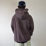 Canguro oversize de algodón color marrón oscuro con efecto lavado desgastado, capucha amplia y gran aplique de tela con bordado en la espalda.