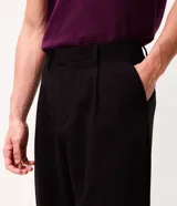 Pantalón de vestir beige de corte wide leg, con trabillas para cinto, bolsillos y diseño de sastrería.