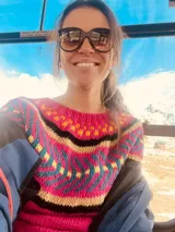 Sweater tejido a mano en lana de color fucsia con diseño geométrico multicolor.