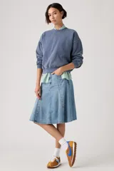 Falda midi de denim en tono azul claro, con diseño acampanado y paneles verticales tipo godet.