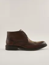 Botas de cuero marrón oscuro estilo brogue, con cordones y suela baja.
