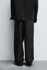 Pantalón de corte relajado en color verde militar, con diseño de pliegues frontales, bolsillos laterales y cierre de cremallera con botón.