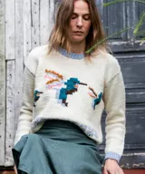 Sweater de lana merino color natural tejido en punto jersey, con diseño jacquard multicolor de aves en el frente y detalles en tono celeste en cuello, puños y ruedo.