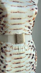 Vestido midi con estampado de piel de serpiente en tonos beige y marrón. Diseño con top halter y falda tubo con abertura lateral.