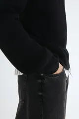 Buzo negro de punto acanalado, con cuello redondo y bajo recto.