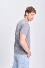 Remera de manga corta color gris con efecto lavado, con estampado en la espalda que incluye una galaxia espiral y texto que dice "Create your own" y "/// GALAXY".