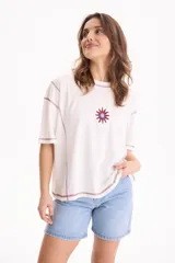 Remera blanca de algodón, corte semi boxy con mangas cortas, costuras en contraste color bordó y detalle bordado de sol en el pecho.