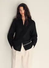 Camisa de lino color negro, de diseño oversize, con cuello camisero, cierre frontal de botones y manga larga con puños abotonados.