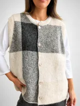 Chaleco de tejido de punto con diseño de cuadros grandes en tonos beige y gris. Presenta un corte oversize, cuello redondo y cierre frontal con botones a tono.