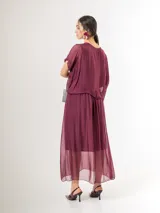Vestido midi de seda italiana color bordó, con escote en V, sobrecapa fruncida y diseño fluido. Cuenta con mangas cortas amplias y elástico en la cintura.
