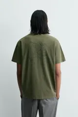 Camiseta de corte relajado, color verde oliva con efecto lavado. Presenta cuello redondo, manga corta y un gráfico estampado en la espalda.