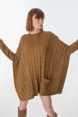 Sweater de punto color camel con hilos dorados, de silueta holgada, cuello redondo y mangas largas con puños ajustados. Presenta un bolsillo de parche con etiqueta de cuero sintético en el frente.