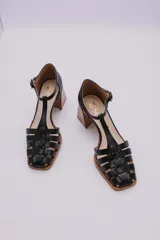 Guillerminas clásicas de cuero negro con diseño de tiras entretejidas, pulsera con hebilla y taco de madera.