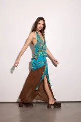 Vestido largo amarillo con escote halter y detalle de volados en el cuello. Presenta un diseño superpuesto con una capa superior estampada a cuadros multicolor con nudo lateral en la cintura y una falda fluida lisa con abertura lateral.