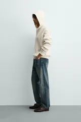 Sudadera de corte relajado confeccionada en tejido de algodón con textura waffle. Presenta cuello con capucha, cierre frontal parcial con botones y mangas largas con puños acanalados.