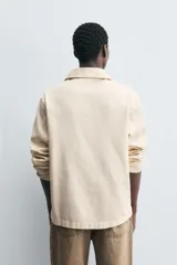 Sobrecamisa de algodón color beige claro, con cuello solapa, abertura frontal en V y manga larga. Presenta un efecto lavado y un calce relajado.