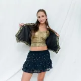 Chaleco corto con estampado abstracto en tonos dorados y azules, escote en V y cierre frontal con botones de madera.