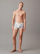 Pack de tres bóxers tipo trunk Calvin Klein de talle bajo, confeccionados en mezcla de algodón y elastano. Incluye uno en color azul, uno gris y uno negro con monogramas estampados. Todos cuentan con cinturilla elástica blanca con el logo de la marca.