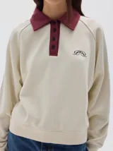 Buzo de friza suave color azul marino, con cuello polo y cartera de botones en contraste azul denim. Mangas raglán con franjas laterales azules y logo bordado en el pecho.