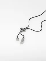 Collar con cordón negro ajustable y colgante rectangular plateado con pieza ovalada blanca en el centro.