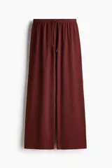 Pantalón de punto bordó de corte holgado con piernas amplias, tiro alto, cintura elástica y cordón ajustable.