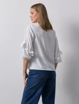 Blusa de gasa estampada con flores azules y violetas sobre fondo blanco, de manga 3/4 con volados.