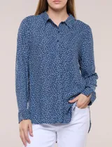 Camisa de rayón azul marino con estampado de lunares pequeños en tonos claros, cuello camisero, cierre frontal de botones, mangas largas y ruedo curvo asimétrico más largo en la espalda.