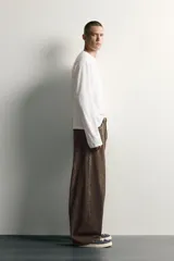 Pantalón barrel fit de mezclilla color verde militar, con efecto lavado, cinco bolsillos, cierre frontal con cremallera y botón, y detalle de pinzas en las rodillas.